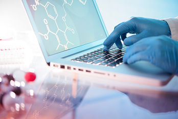 Scientist with gloves using a laptop