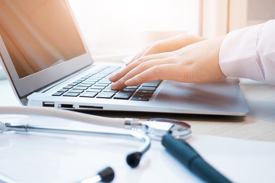 Doctor typing information on the computer in office