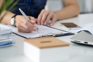 Close-up of female hands. Woman writing something on piece of paper