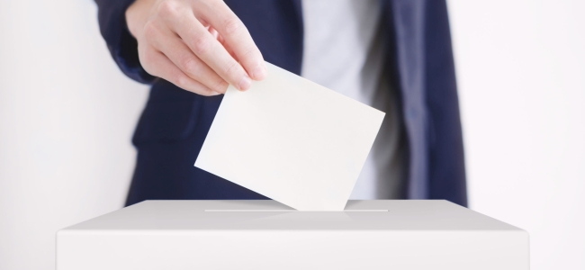 Man putting a ballot into a voting box.