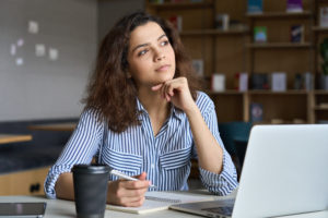 Young woman thinking at computer