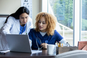 Doctor and her nurse having a conversation in front of computer