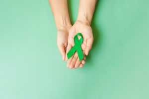 Hands holding green awareness ribbon