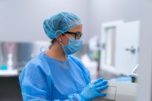 Female health professional wearing scrubs and hairnet in lab