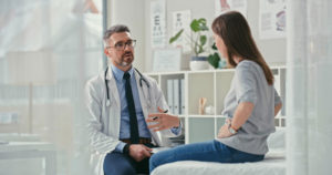 Physician talking to patient holding stomach