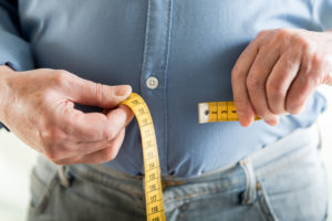 Man holding tape measure to stomach