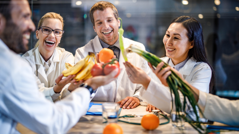 Group of doctors holding up fruits and vegetables