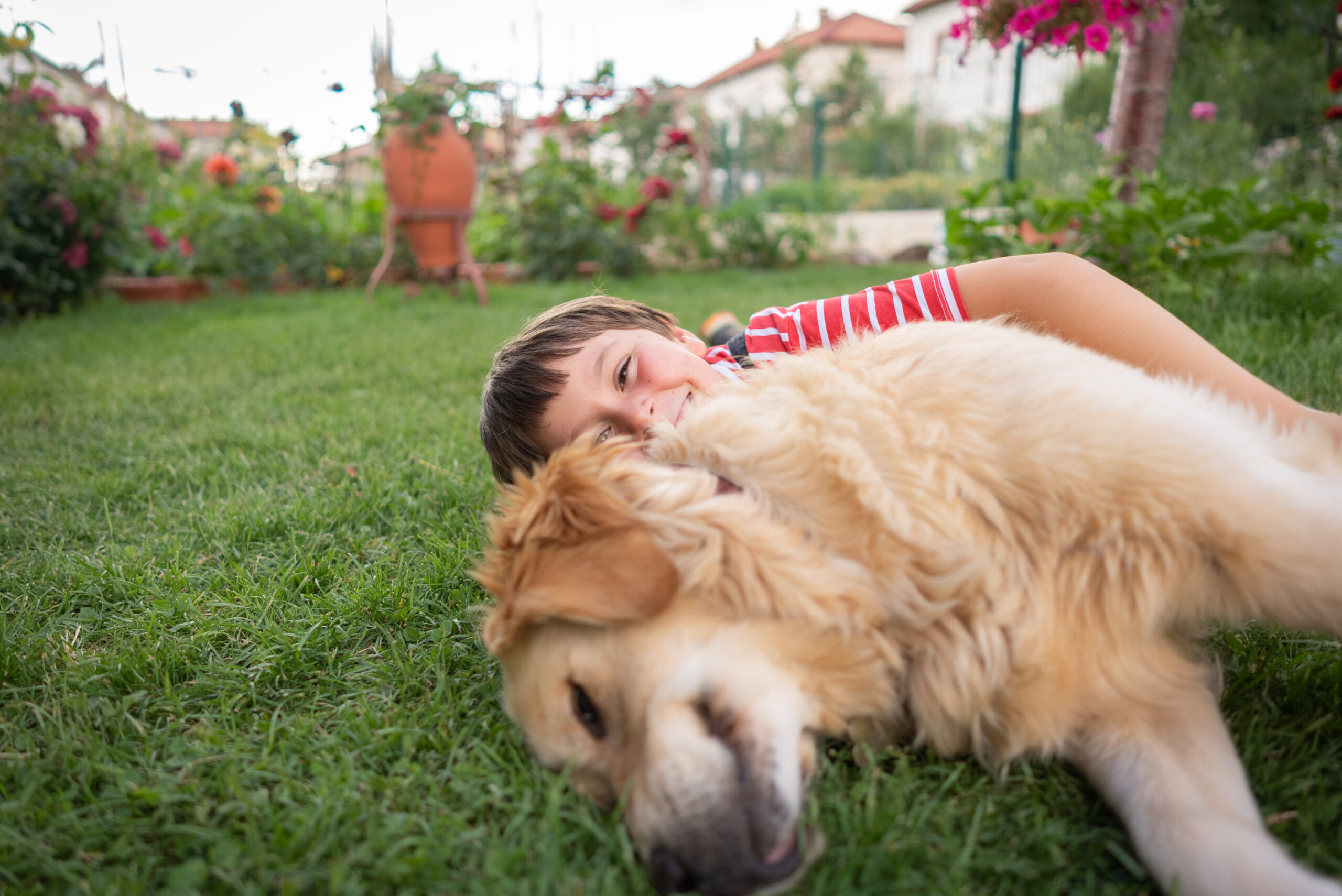 Small child hugging dog outside