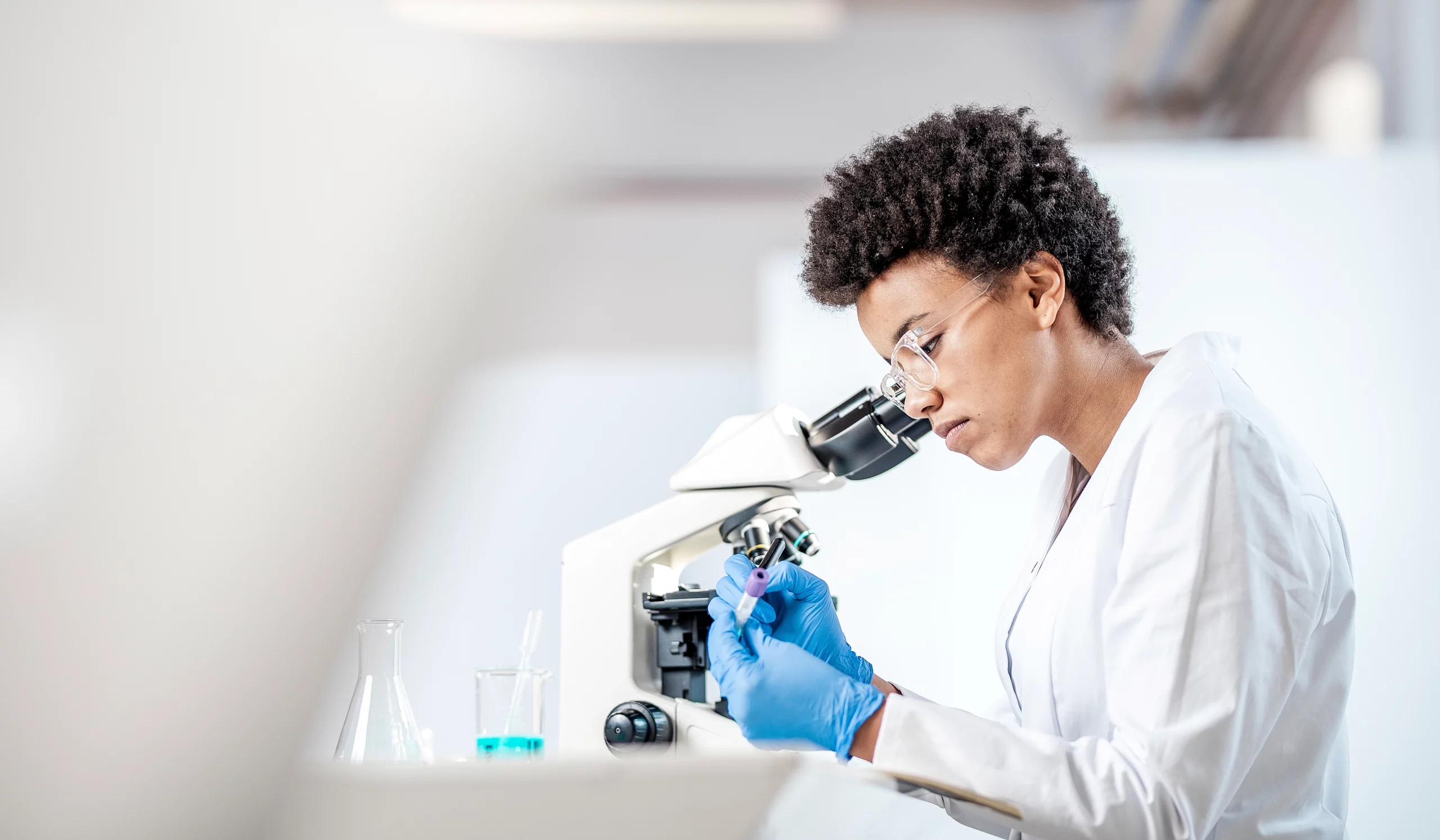 Young female scientist looking into microscope