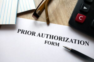 Prior authorization form with pen, calculator and glasses on desk