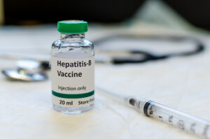 Fake hepatitis B vaccine vial with syringe and stethoscope at the background