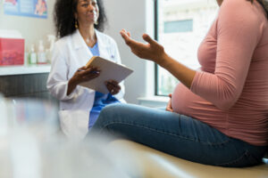 Unrecognizable pregnant woman gestures while talking to obstetrician