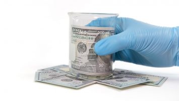 Hand and beaker of money Hand grabs beaker with rolled currency