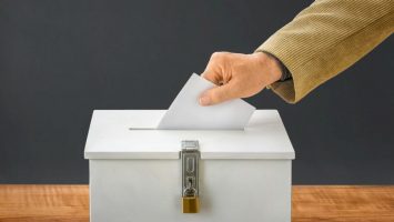 Man putting a ballot into a voting box