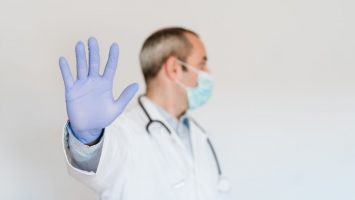 portrait of doctor wearing protective mask and gloves indoors. Making a stop sign with hand. Corona virus concept portrait of doctor wearing protective mask and gloves indoors. Making a stop sign with hand. Corona virus concept