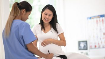 Hispanic Pregnant Woman Speaks With Her Doctor at a Check-Up stock photo A woman discuses her prenatal health during a routine check up with her obstetrician