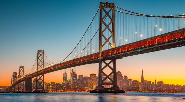 Classic panoramic view of San Francisco skyline with famous Oakland Bay Bridge illuminated in beautiful golden evening light at sunset in summer, San Francisco Bay Area, California, USA