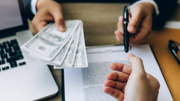 Partner has made a fraud in the contract of sale and being handed a cash and pen to the businessman signing the contract corruption bribery concept. Partner has made a fraud in the contract of sale and being handed a cash and pen to the businessman signing the contract corruption bribery concept.