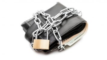 Chain padlock on leather wallet full of dollar currency money Business safety and finance protection concept - metal chain link with locked padlock on leather wallet full of dollar currency money white isolated