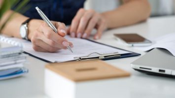 Woman writing something sitting at her office Close-up of female hands. Woman writing something sitting at her office
