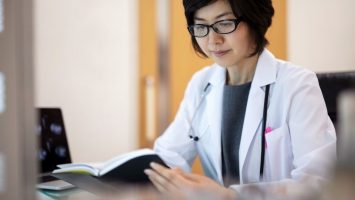 Japanese Female radiologist reading diary at desk in hospital Doctor reading study at desk