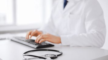 healthcare, people and medicine concept - close up of  male doctor typing on the keyboard at hospital