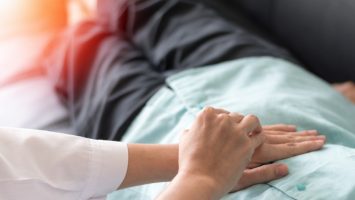 Patient with doctor checking on stomach diseases or gastropathy include gastritis, gastroparesis, diarrhea on senior old female person in hospital. Doctor Hand On Patient Stomach