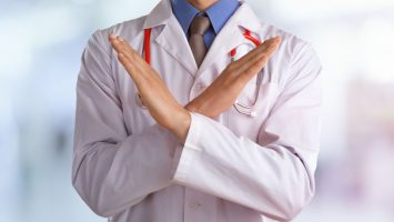 Young doctor with a stethoscope shows stop sign with his hands Young doctor shows stop sign with hands on abstract gradient background