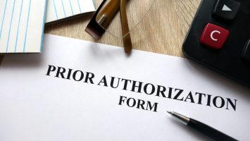 Prior authorization form with pen, calculator and glasses on desk