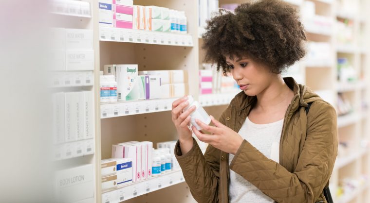 Young Woman Choosing Supplement In Drugstore
