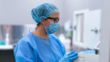 Female health professional wearing scrubs and hairnet in lab