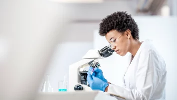 Young female scientist looking into microscope