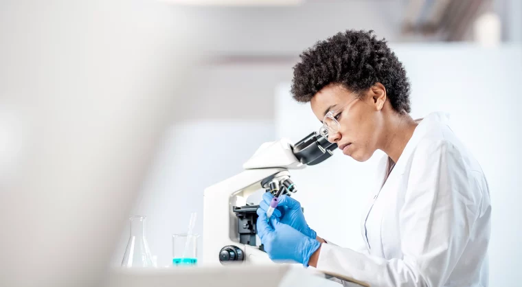 Young female scientist looking into microscope