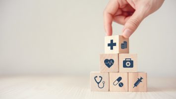 Health Insurance Concept, Reduce Medical Expenses, Hand flip wood cube with icon healthcare medical and coin on wood background, copy space.