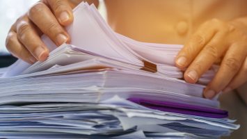 Businesswoman hands working in Stacks of paper files for searching information on work desk office, business report papers,piles of unfinished documents achieves with clips indoor,Business concept