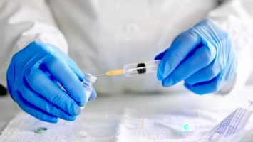 Doctor fills injection syringe with vaccine