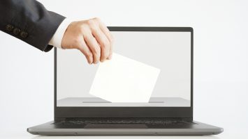 Voting Online Concept. Man Putting a Ballot into a Laptop.