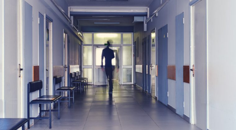 Blurred silhouette of a man passing away through the hospital hallway. The concept of problems of recovery and exit from the clinic