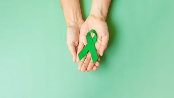 Hands holding green awareness ribbon