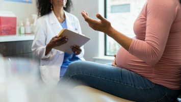 Unrecognizable pregnant woman gestures while talking to obstetrician