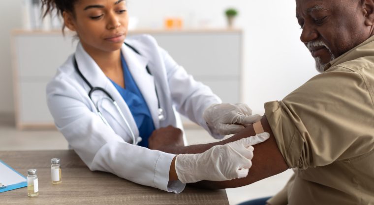 Black Mature Man Getting Vaccinated, Doctor Applying Adhesive Bandage