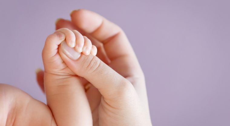 Newborn children's hand in mother hand. Mom and her Child. Happy Family concept. Beautiful conceptual image of Maternity