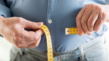 Man holding tape measure to stomach
