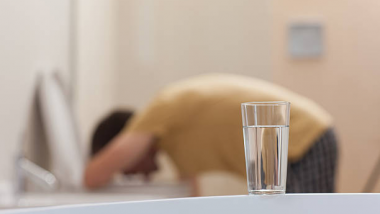 Man hunched down on toilet vomiting