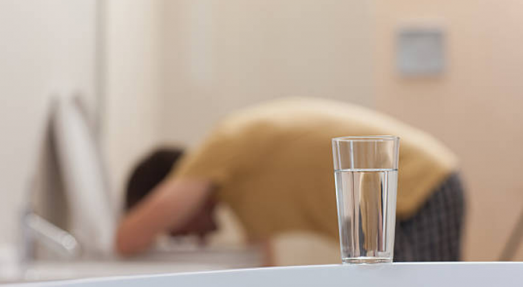 Man hunched down on toilet vomiting