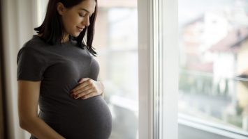 Portrait of young happy pregnant woman standing by the window Portrait of young happy pregnant woman standing by the window