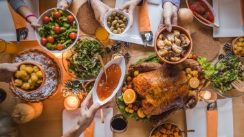 Above view of passing food during Thanksgiving dinner. High angle view of unrecognizable people passing side dishes during Thanksgiving dinner at dining table.
